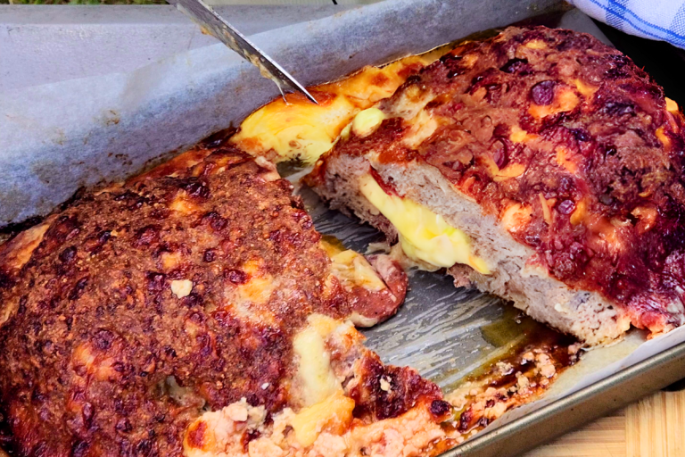 Baked cheese-stuffed Italian meatloaf sliced open to reveal gooey melted cheese and salami.