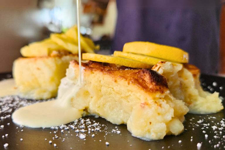Close-up of lemon delicious pudding being served with pouring cream