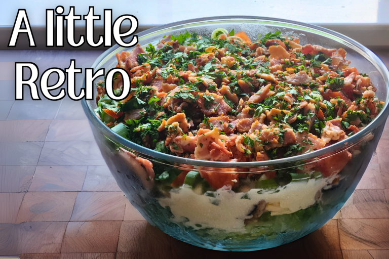 Layered salad with eggs, peas, bacon, cheese, and creamy dressing in a glass bowl.