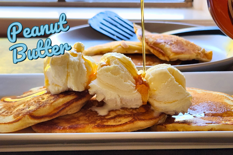 Stack of fluffy peanut butter pancakes served with cream and syrup