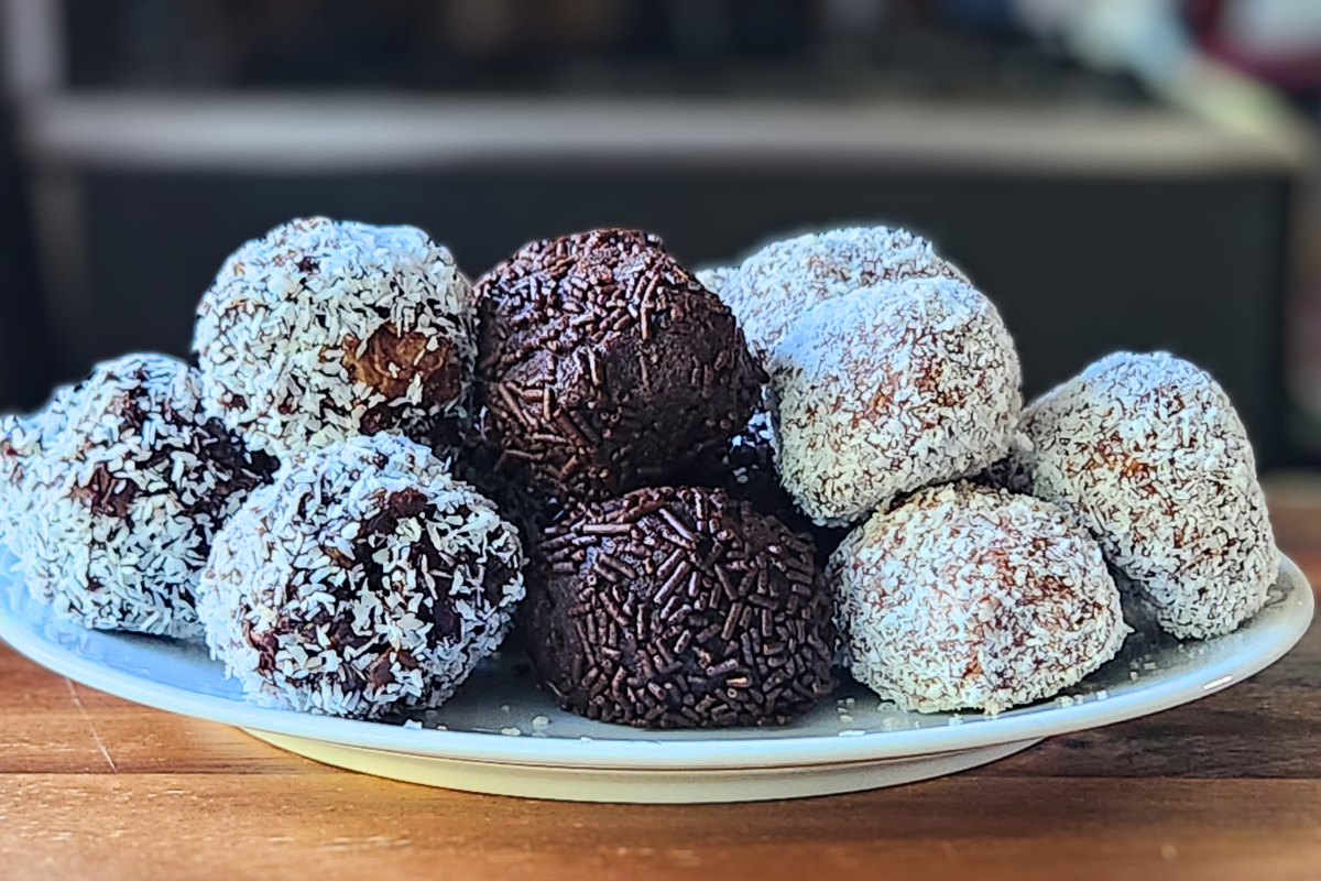 A plate of rum balls with chocolate sprinkles and coconut coatings.