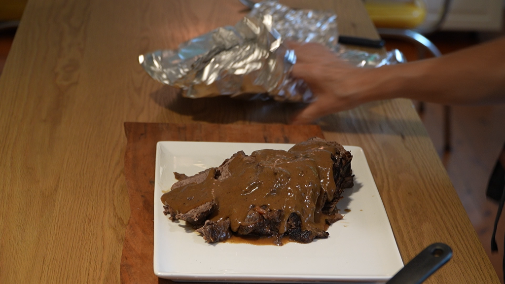 Sliced beef topped with Sauerbraten sauce on a white platter, ready to serve