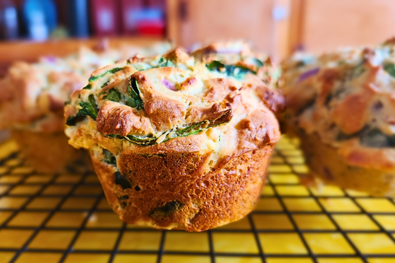 Freshly baked savoury muffins with spinach, feta, and parmesan cheese.
