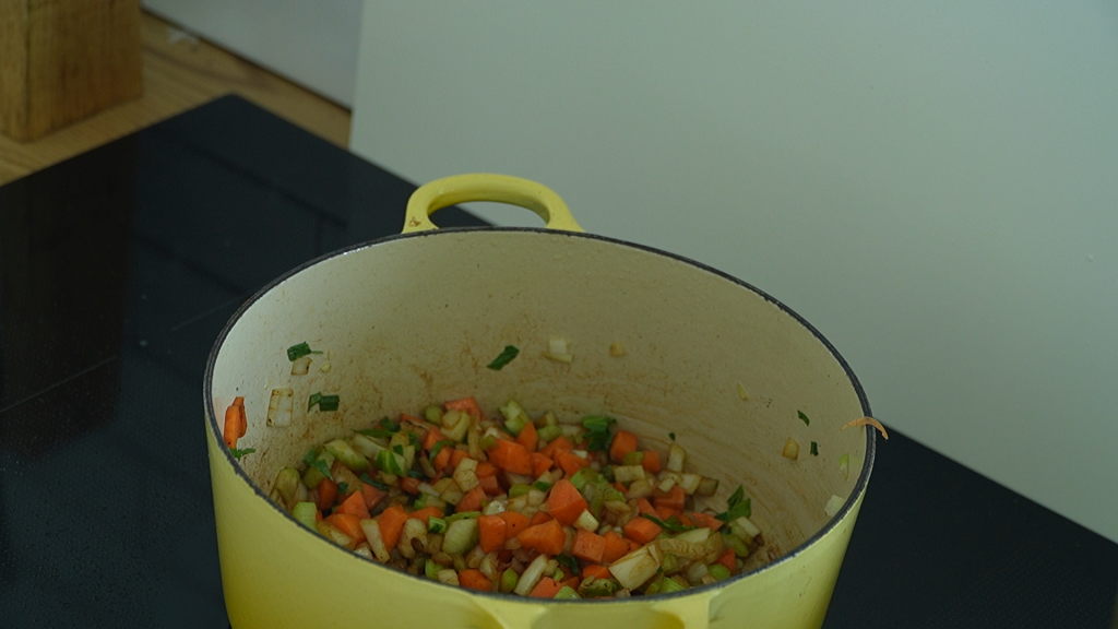 Chopped carrots, celery, and onions softening in a yellow Dutch oven.