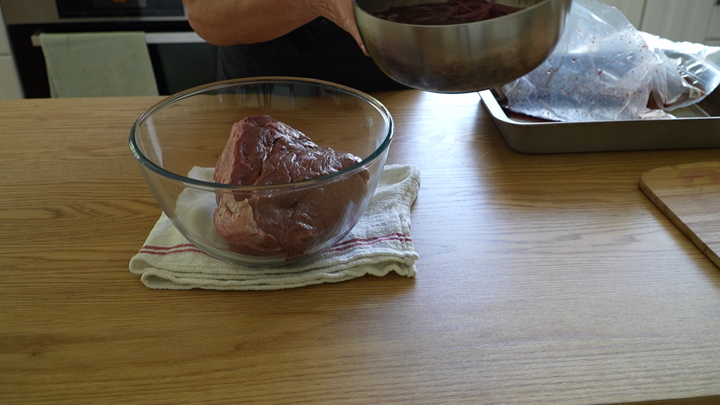 A raw piece of topside beef in a glass bowl, ready for marinating