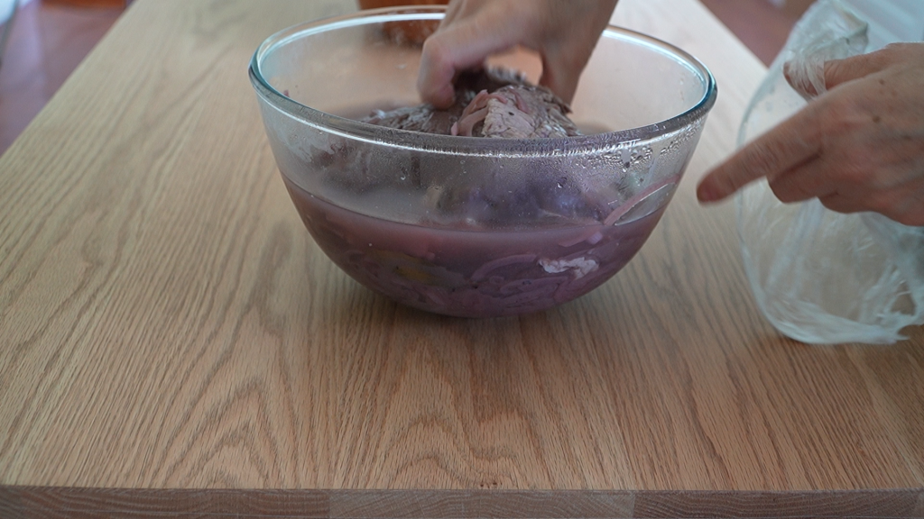 Turning topside beef in marinade by hand, showing the deep red colour