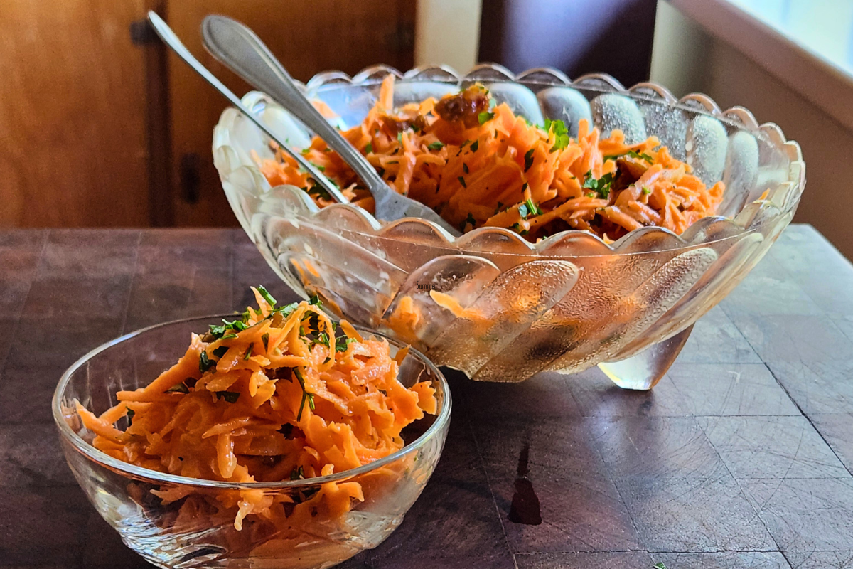 Grated carrot salad served in small and large vintage glass bowls, garnished with parsley