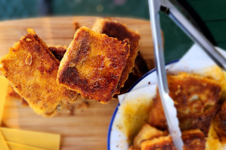 Close-up of crispy golden lasagna toppers stacked on a board