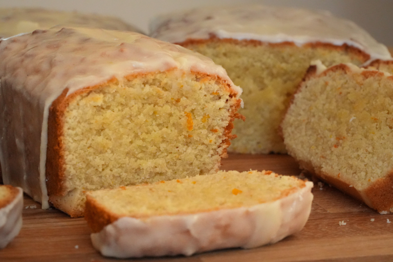 Almond Genoa Cake sliced on a wooden board with lemon glaze