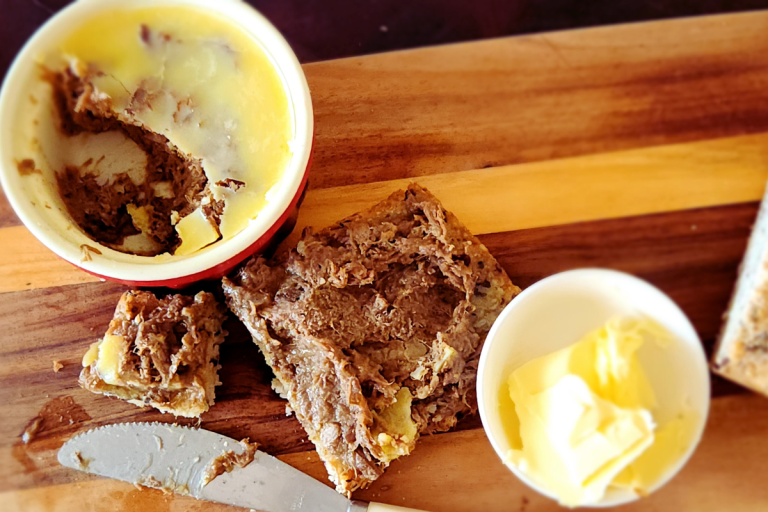 Close-up of potted beef spread on toast next to a ramekin with butter
