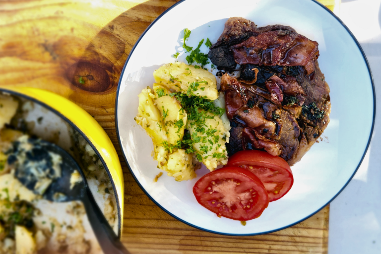 Salsa Verde potatoes with Portuguese steak and tomato slices on a plate