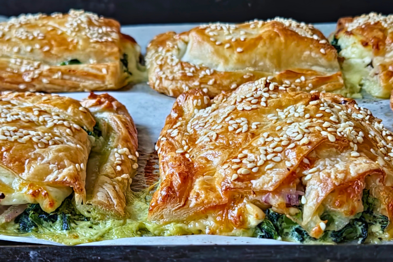 Golden spinach and feta puff pastries topped with sesame seeds, baked until flaky and crisp.