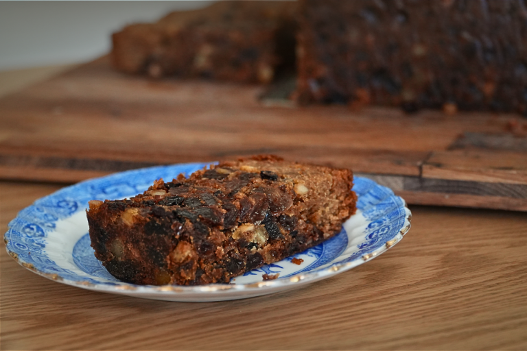 Close-up slice of 100-year-old fruit cake on a vintage blue-and-white plate.