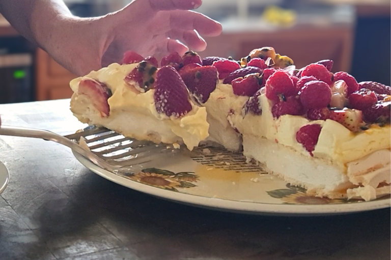 Slice of Australian pavlova showing a soft marshmallow centre with whipped cream and berries