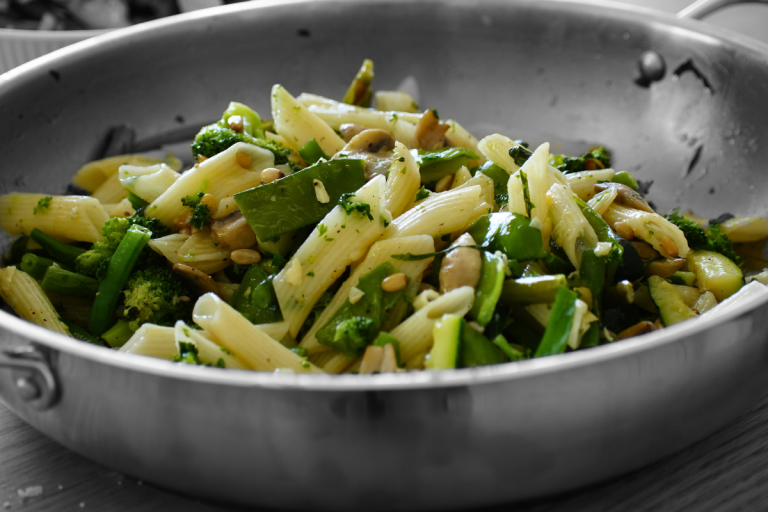 Penne pasta primavera with broccoli, asparagus, beans, and mushrooms in a pan