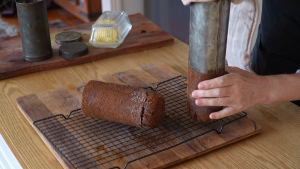 Removing baked date and walnut loaf from a traditional old-fashioned roll tin