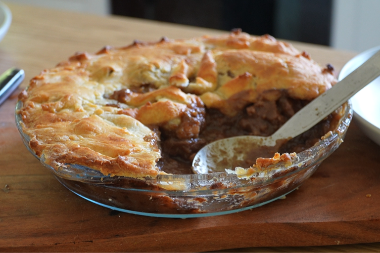 Homemade Aussie steak pie with golden pastry and tender beef in rich gravy
